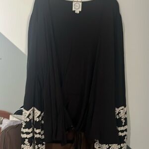 Black long sleeve top with white embroidery on bottom of sleeve